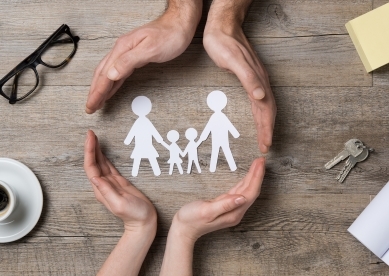 Family paper cut out surrounded by hands